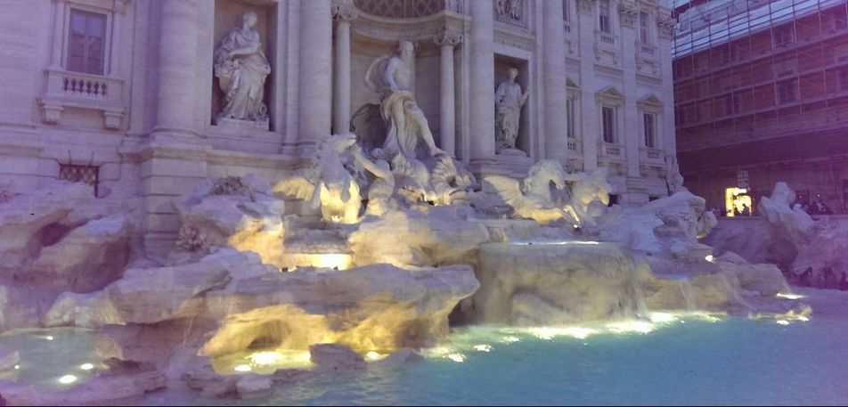 Trevi fountain at night, lit with blue lights.