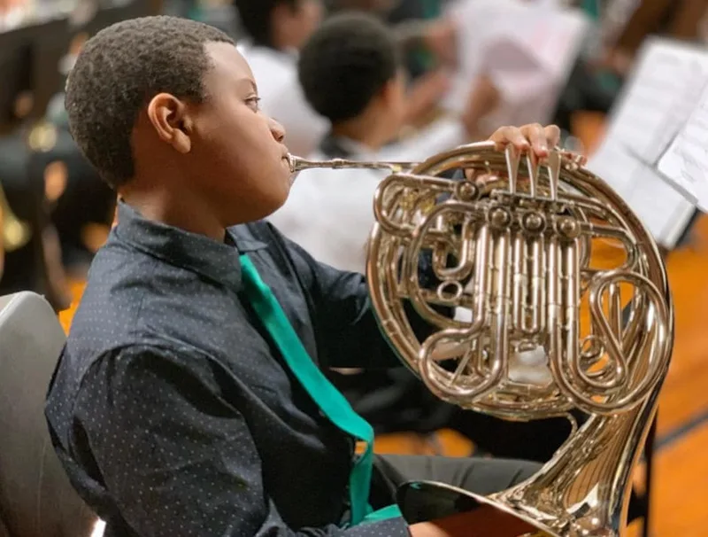 Photograph of a student playing a French horn. 
