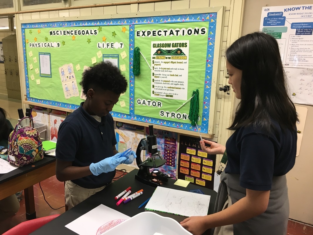 A male student and a female students are working with a microscope.