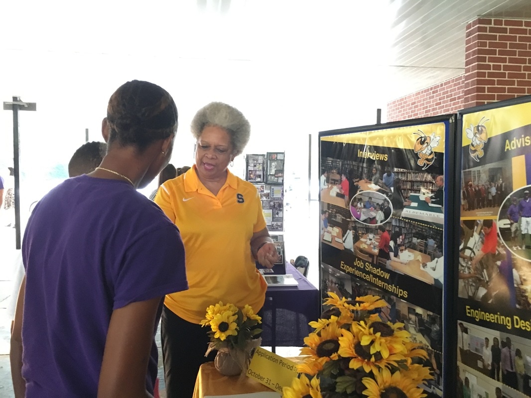 A student and a parent speak with a representative from a local high school. 