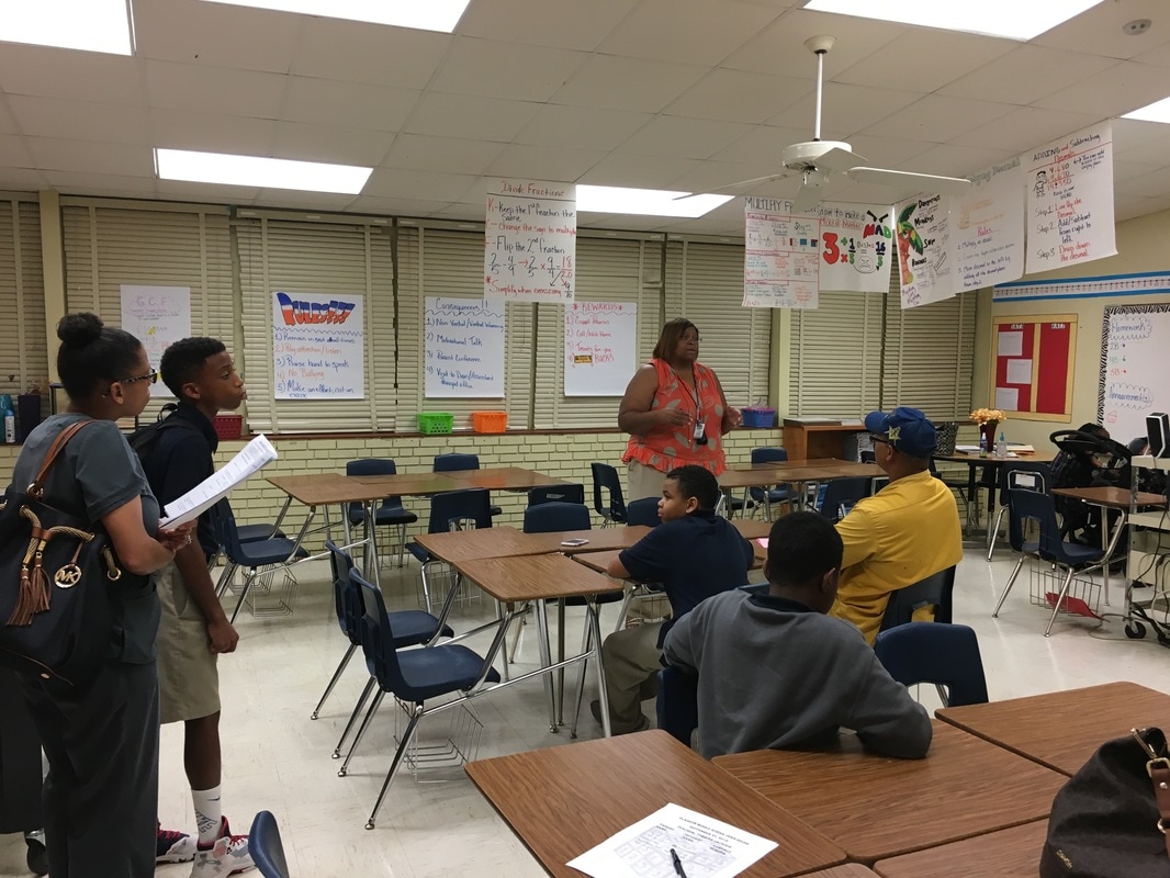 Parents listen to a teacher's open house presentation. 