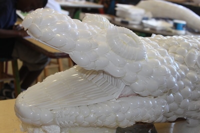 A sculpture of an alligator head. The sculpture is made from sporks from the school cafeteria.
