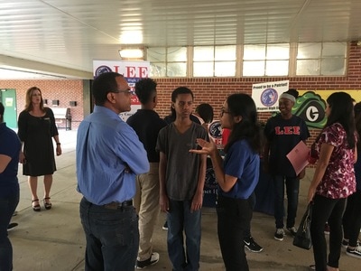 A student and a parent speak with a student representative from a local high school.