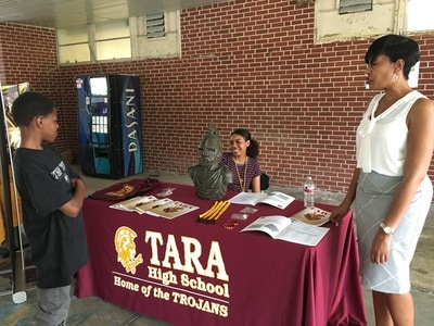 A student speaks with two representatives from a local high school. 